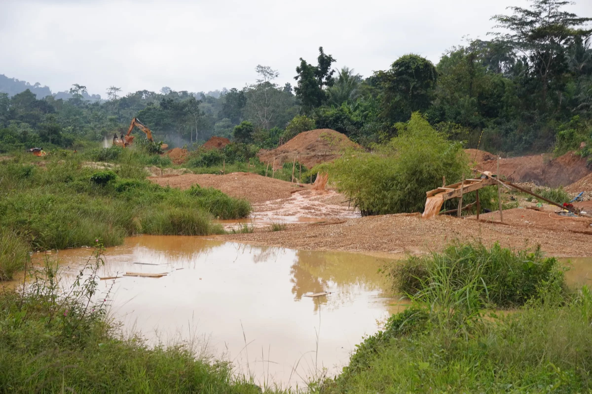 Galamsey-stripped ground in the project area, a standing pool of water among the ridges and pits left by the workings