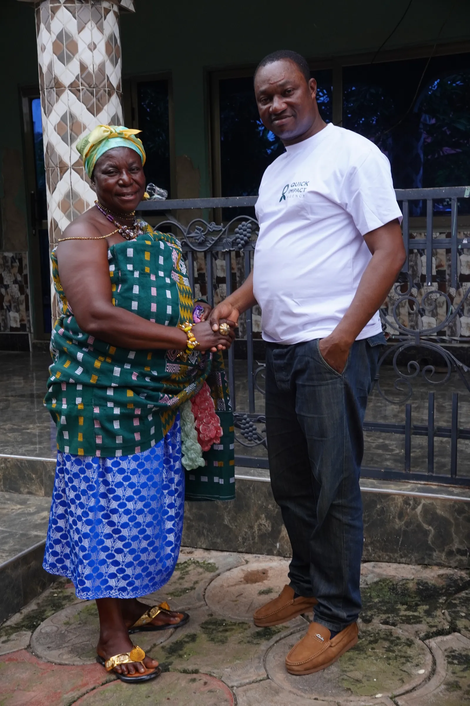 A queen mother in kente in conversation with a member of the QIA team