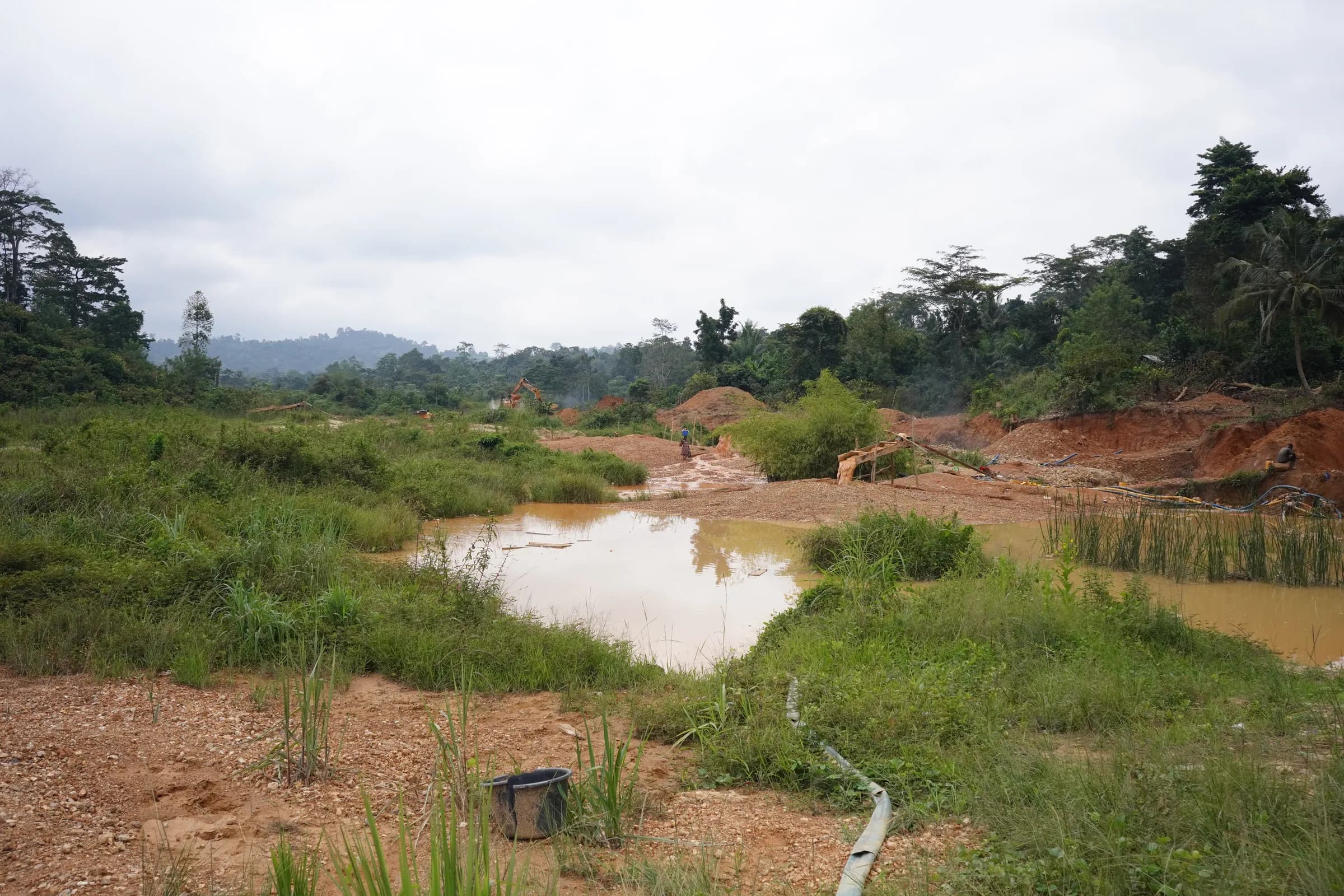 Mined ground beginning to green over, grass and scrub returning across the tailings between the pits