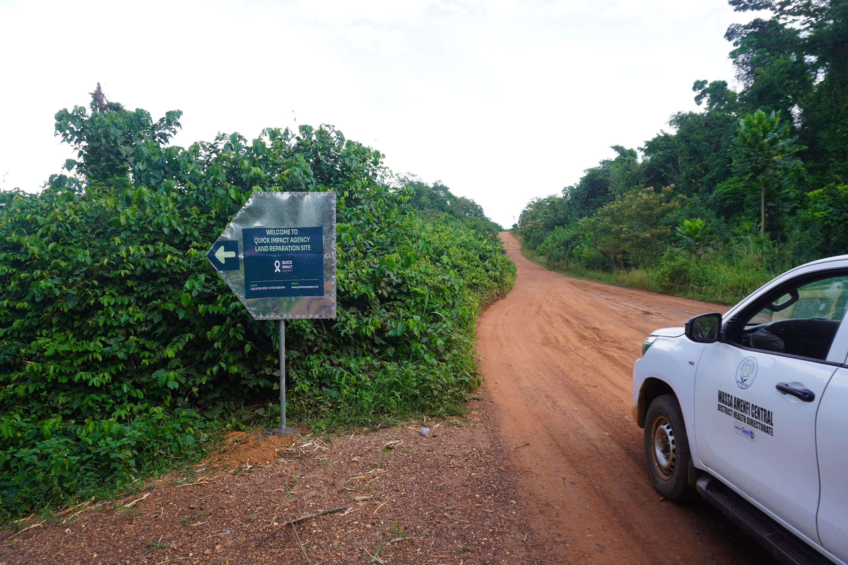 The road into the QIA land reparation site in Western North, Ghana, with the site sign at the turning